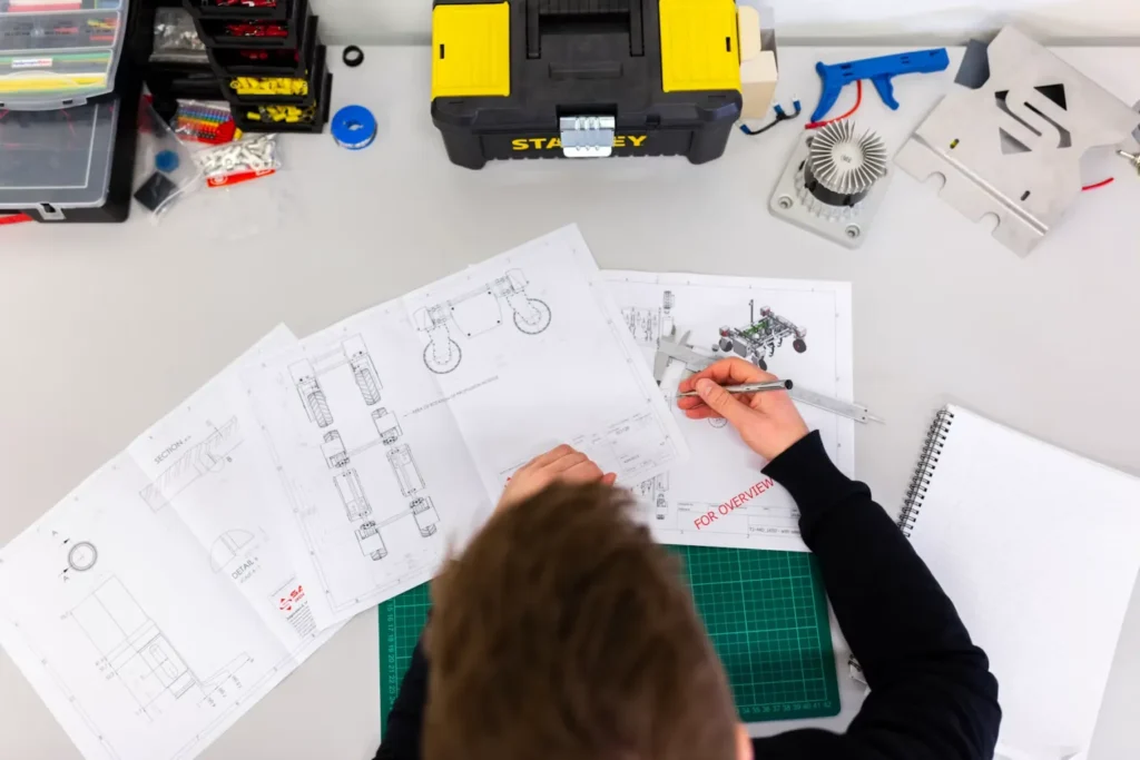 High-angle shot of an engineer reviewing technical engineering schematics and blueprints.