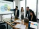 A diverse four-person business team discusses an 'INTEGRATED METHODOLOGY' diagram on a projector screen, which visually links 'ORGANIC AUTHORITY', 'AI SEARCH VISIBILITY', and 'CONTENT STRATEGY' within a modern Sydney office overlooking the Opera House.