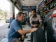 A mechanic showing a car owner a brand new tyre at a discount tyre shop in Dubai, UAE.
