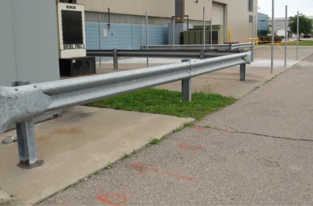A heavy-duty steel W-beam guardrail installed in an industrial area to provide a protective traffic barrier.
