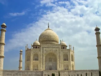 The white marble Taj Mahal in Agra, India, framed by a blue sky with soft white clouds, representing bespoke luxury travel.