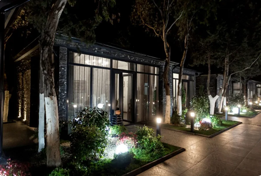 Modern residential building at night illuminated by high-quality U.S. outdoor landscape path lights, wall wash lights, and orb garden lights.
