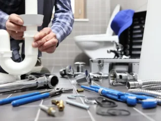 A plumber assembling white plastic and chrome piping surrounded by tools on a tiled floor, preparing for gas or utility infrastructure work.
