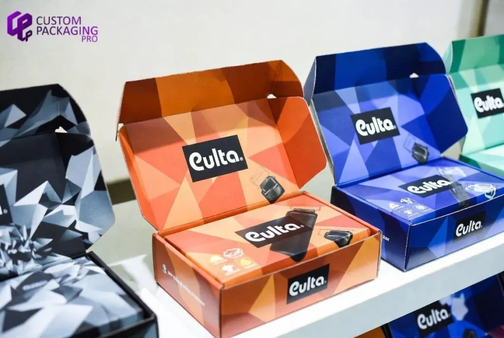 Open custom-printed kraft mailer boxes featuring vibrant geometric patterns and "Culta" branding displayed on a shelf.
