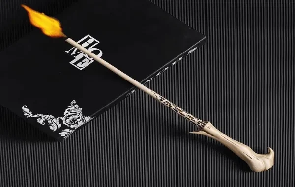 A replica Elder Wand shooting a small flame from its tip, resting on a black box.