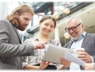 An HR consultant reviewing strategy documents on a tablet with two diverse colleagues in a modern office building.