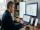 A man at a wooden desk configures Libero Mail IMAP and SMTP settings on a laptop, a vertical monitor, a regular monitor, an iPhone, and an Android smartphone, all open to email account setup screens.
