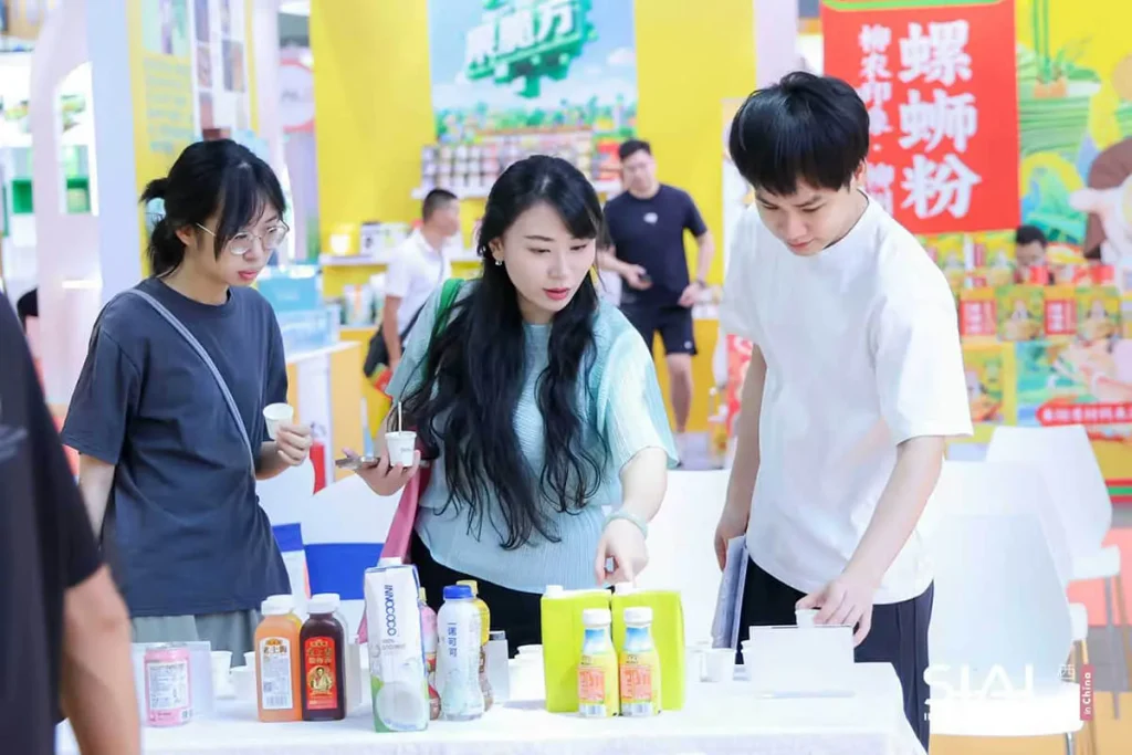 Attendees exploring food and beverage products and sampling drinks at a global exhibition booth.