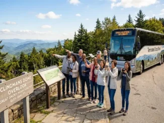 A diverse group of tourists taking photos at the Clingmans Dome Overlook in the Great Smoky Mountains, with a modern tour charter bus parked nearby.