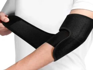 Person wrapping a black adjustable neoprene elbow brace with a Velcro strap around their arm for joint support.