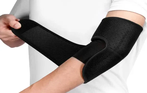 Person wrapping a black adjustable neoprene elbow brace with a Velcro strap around their arm for joint support.