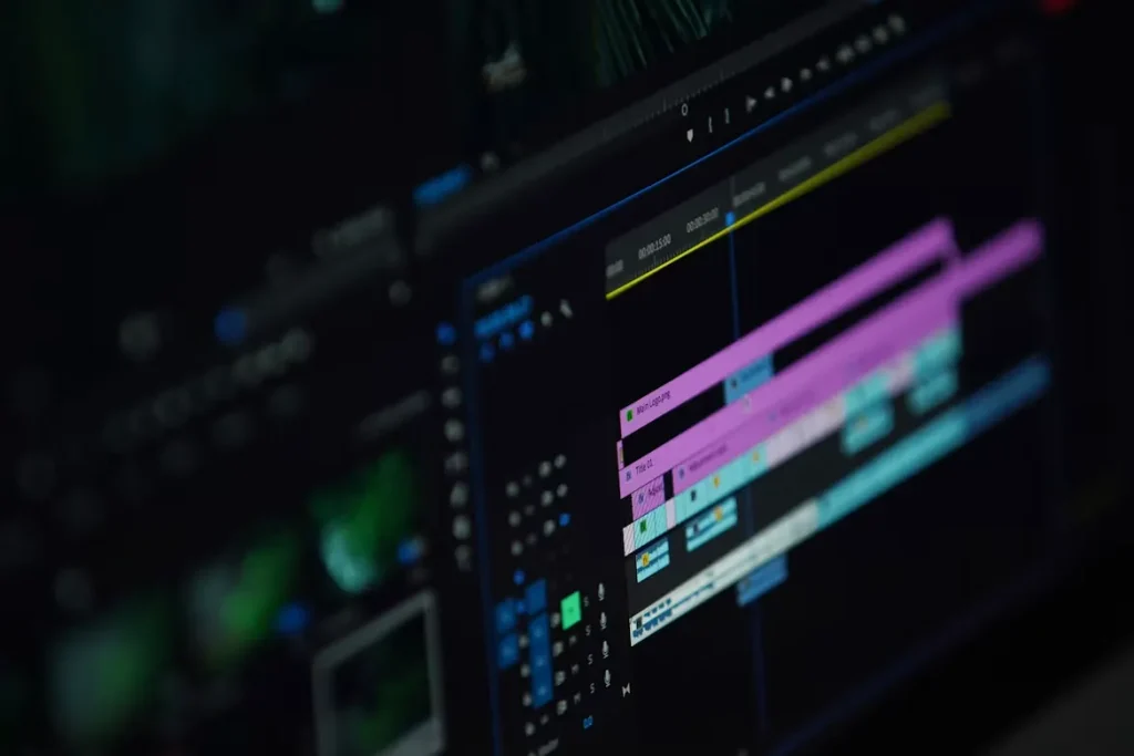 Close-up view of a digital video editing workspace timeline displaying color-coded media tracks, audio channels, and keyframe markers on a monitor screen.