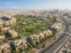 High-angle architectural rendering of the Azizi Florence community in Sharjah, showing modern townhouses, villas, a central park, and surrounding road infrastructure.