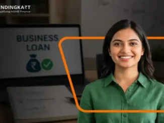 Smiling Indian female entrepreneur standing in front of a laptop displaying a business loan approval graphic.
