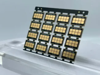 Grid array of small high-frequency printed circuit board modules with gold-plated pads resting on a clear stand.