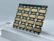 Grid array of small high-frequency printed circuit board modules with gold-plated pads resting on a clear stand.