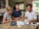A professional painting contractor discussing scope, color fan decks, and a written estimate with a couple at a kitchen table.