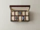 An open wooden watch display box with ten slots, containing only three wristwatches, symbolizing a growing collection.
