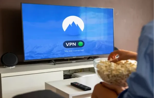 A person holding a bowl of popcorn watching a Smart TV that displays the NordVPN app screen with a green "You are connected" status indicator.