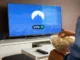 A person holding a bowl of popcorn watching a Smart TV that displays the NordVPN app screen with a green "You are connected" status indicator.