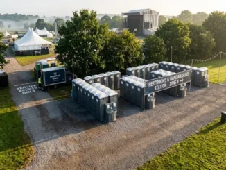 High-angle view of organized portable restrooms and handwashing stations lined up in a designated event zone with a service truck nearby.