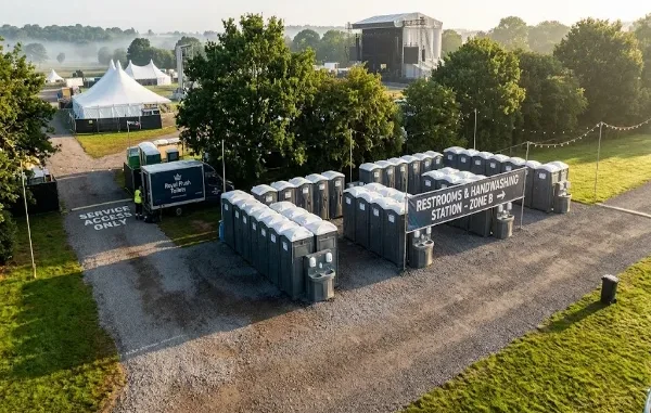 High-angle view of organized portable restrooms and handwashing stations lined up in a designated event zone with a service truck nearby.