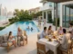 A multi-generational family enjoying a meal and relaxing on a luxury waterfront villa terrace with an infinity pool and the Dubai skyline in the background.