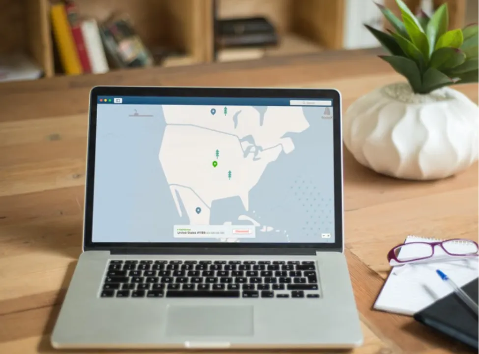 Laptop sitting on a wooden desk displaying a VPN application map with connected server locations in North America.
