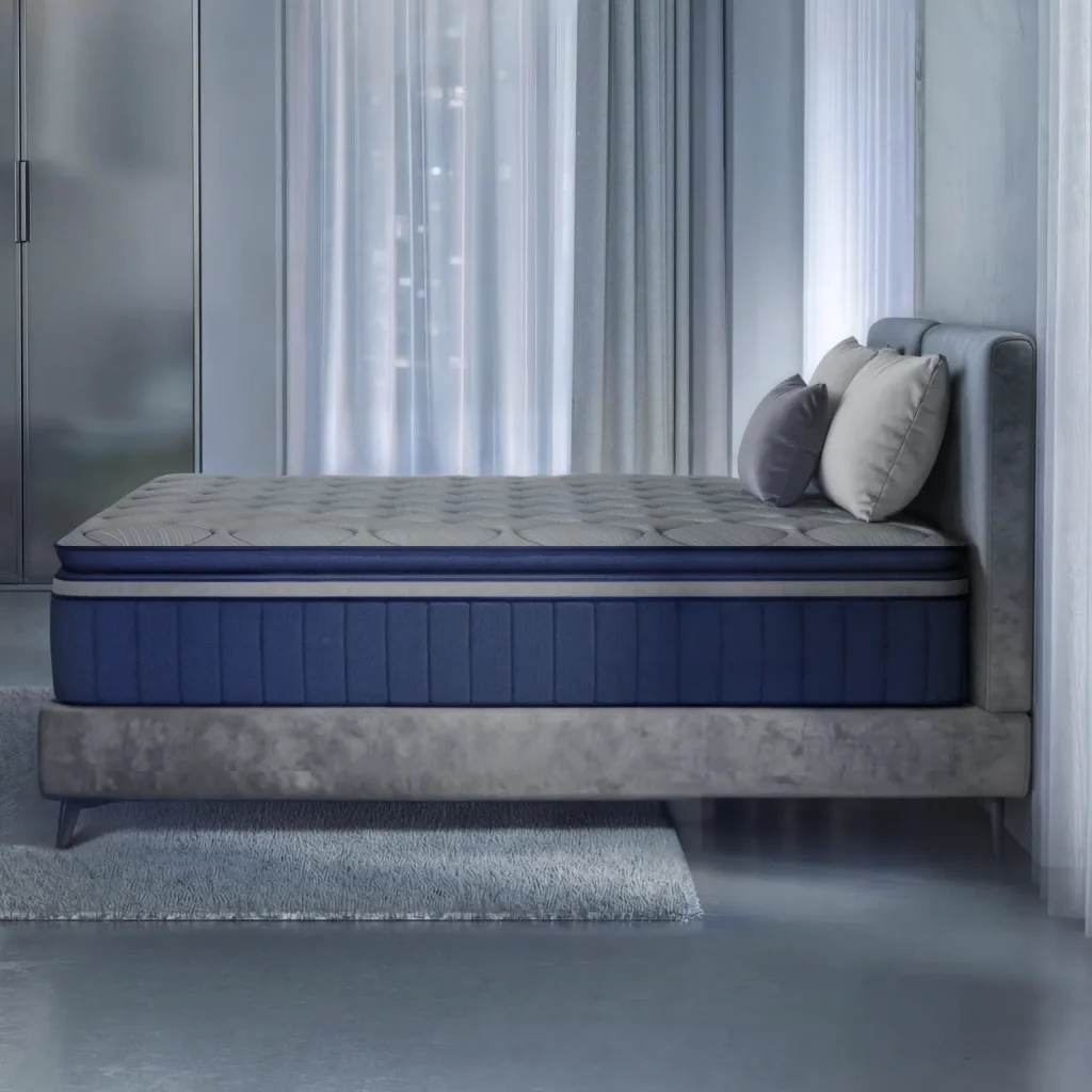 Side view of a thick blue and grey mattress resting on a modern grey upholstered adjustable bed frame in a contemporary bedroom with cool lighting.