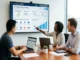 A diverse team of SEO professionals in a modern office analyzing a backlink strategy dashboard for casino search engine optimization on a large wall screen.