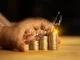Hands safeguarding stacks of coins with a glowing upward financial chart, illustrating smart budgeting strategies for Dhanteras gold purchases.