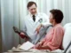 A doctor in a white lab coat discussing medical records with a patient resting in a hospital bed.