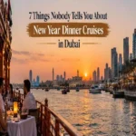 Guests dining on a traditional wooden dhow cruise in Dubai during a vibrant sunset with the city skyline in the background.