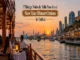 Guests dining on a traditional wooden dhow cruise in Dubai during a vibrant sunset with the city skyline in the background.