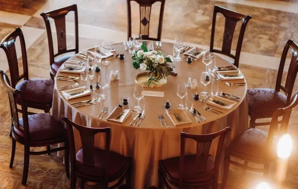 Overhead view of a round banquet table set with rented gold-toned place settings, matching napkins, glassware, and cutlery for a wedding reception.