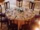 Overhead view of a round banquet table set with rented gold-toned place settings, matching napkins, glassware, and cutlery for a wedding reception.
