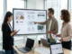 Team of three professionals in a modern office looking at a presentation monitor and discussing Headless Commerce Architecture for multiple storefronts.