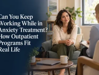 A smiling woman sitting comfortably in an armchair during an outpatient therapy session, speaking with a therapist taking notes in a bright, cozy office setting.